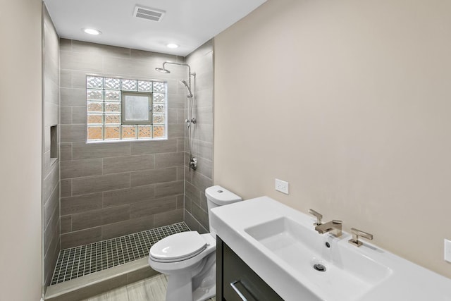 bathroom with tiled shower, vanity, and toilet