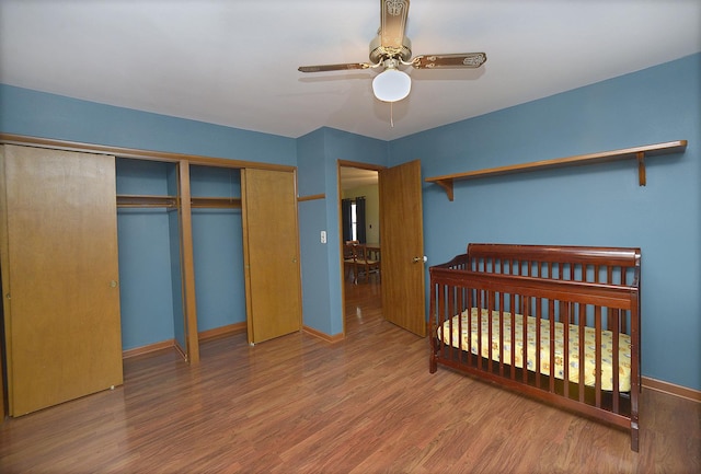 bedroom with a closet, hardwood / wood-style flooring, a nursery area, and ceiling fan