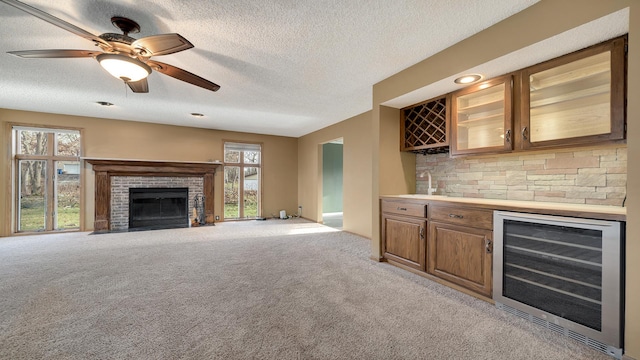 2239 Pine Bluff Dr, Dixon, IL 61021 - indoor dry bar featuring wine cooler, light colored carpet, a textured ceiling, a fireplace, and a ceiling fan