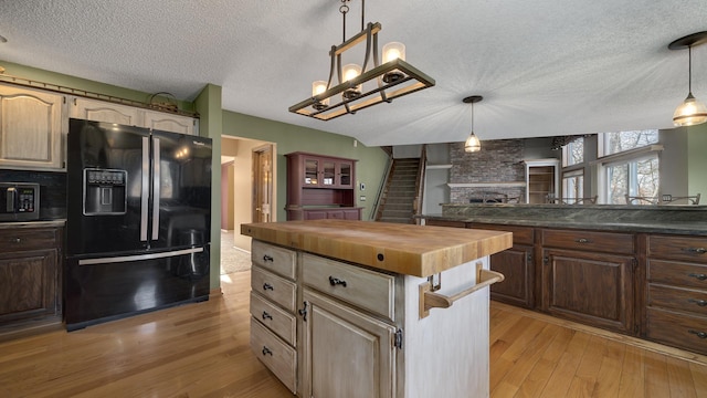 2239 Pine Bluff Dr, Dixon, IL 61021 - kitchen featuring black refrigerator with ice dispenser, wooden counters, a fireplace, light wood-type flooring, and a textured ceiling