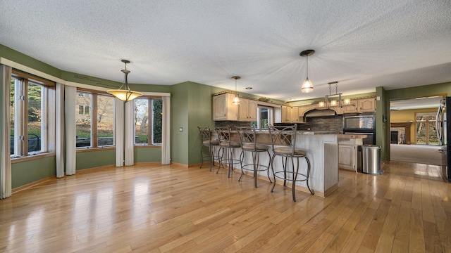 2239 Pine Bluff Dr, Dixon, IL 61021 - kitchen featuring a peninsula, a textured ceiling, decorative backsplash, a breakfast bar, and light wood-style floors