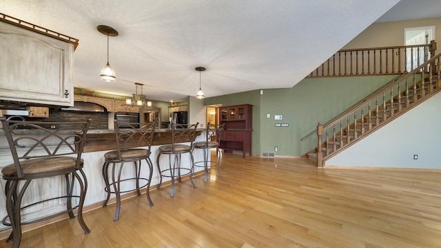 2239 Pine Bluff Dr, Dixon, IL 61021 - kitchen with freestanding refrigerator, light wood finished floors, dark countertops, a kitchen bar, and a peninsula