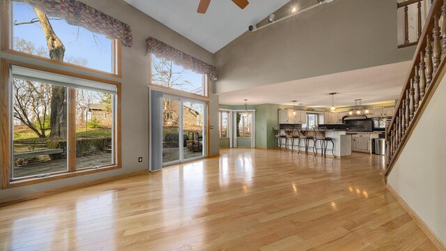 2239 Pine Bluff Dr, Dixon, IL 61021 - unfurnished living room featuring ceiling fan, light wood-type flooring, a towering ceiling, baseboards, and stairway