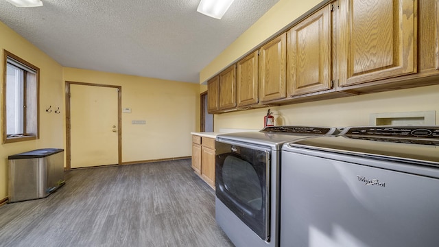 2239 Pine Bluff Dr, Dixon, IL 61021 - laundry area featuring cabinet space, wood finished floors, a textured ceiling, washing machine and clothes dryer, and baseboards