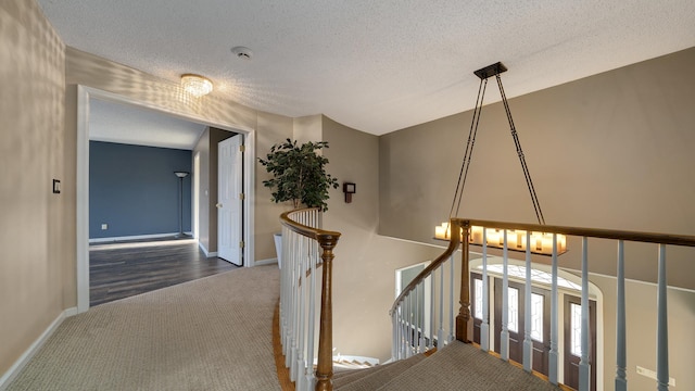 2239 Pine Bluff Dr, Dixon, IL 61021 - hall featuring an upstairs landing, carpet, a textured ceiling, baseboards, and a chandelier