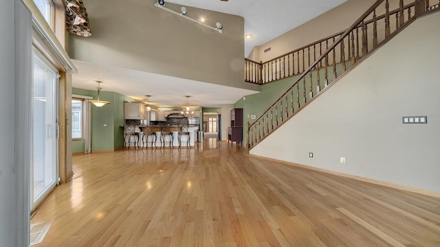 unfurnished living room with a towering ceiling and light hardwood / wood-style floors