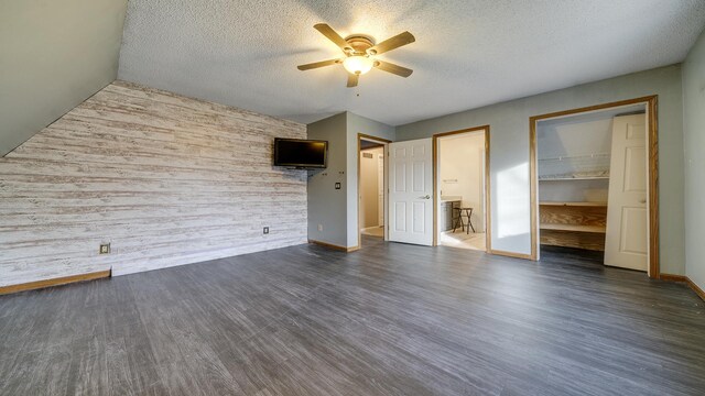 2239 Pine Bluff Dr, Dixon, IL 61021 - unfurnished bedroom featuring dark wood-type flooring, a textured ceiling, a spacious closet, a ceiling fan, and wooden walls