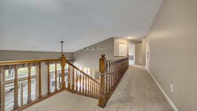 hall featuring light carpet, a textured ceiling, and vaulted ceiling