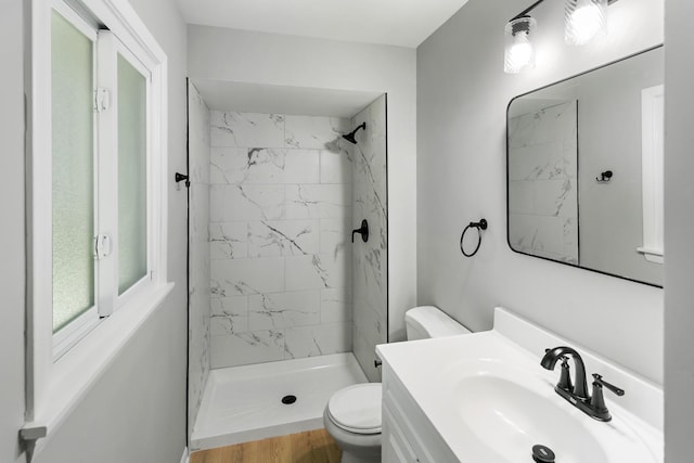 bathroom featuring tiled shower, vanity, hardwood / wood-style flooring, and toilet