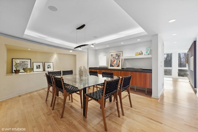 dining area with a tray ceiling and light hardwood / wood-style floors