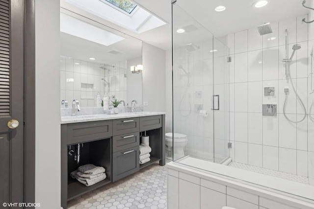 bathroom featuring a skylight, an enclosed shower, vanity, tile patterned flooring, and toilet