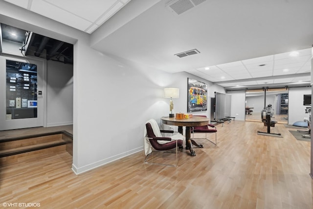 dining space featuring a paneled ceiling and light hardwood / wood-style flooring