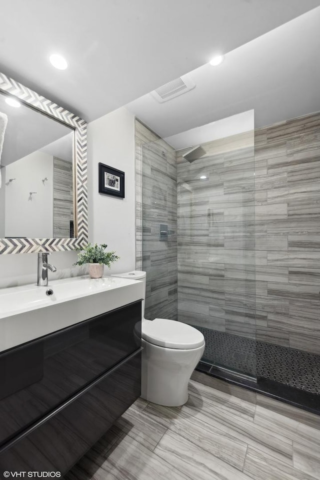 bathroom featuring vanity, toilet, and a tile shower