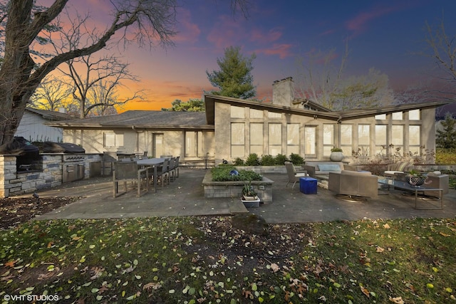 patio terrace at dusk with an outdoor living space, an outdoor kitchen, and a grill