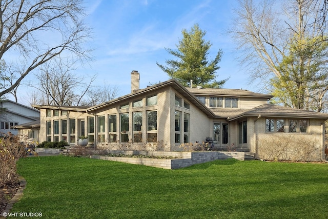 rear view of property featuring a lawn and a sunroom