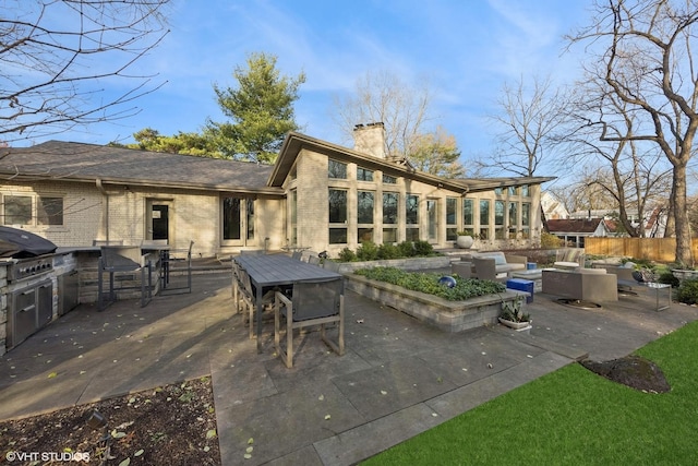 back of house featuring exterior kitchen, a patio area, and an outdoor hangout area