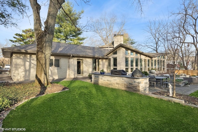 back of property featuring a patio, a lawn, and exterior kitchen