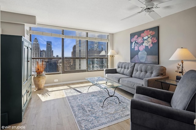 living room with a textured ceiling, light hardwood / wood-style flooring, and ceiling fan