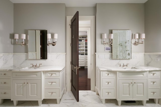 full bath with tile walls, marble finish floor, two vanities, and a sink