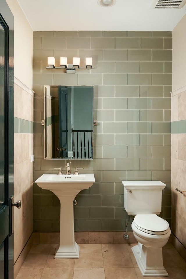 bathroom with tile walls, toilet, visible vents, and tile patterned flooring