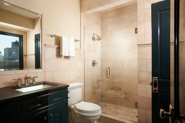 full bath featuring a stall shower, vanity, tile walls, and toilet