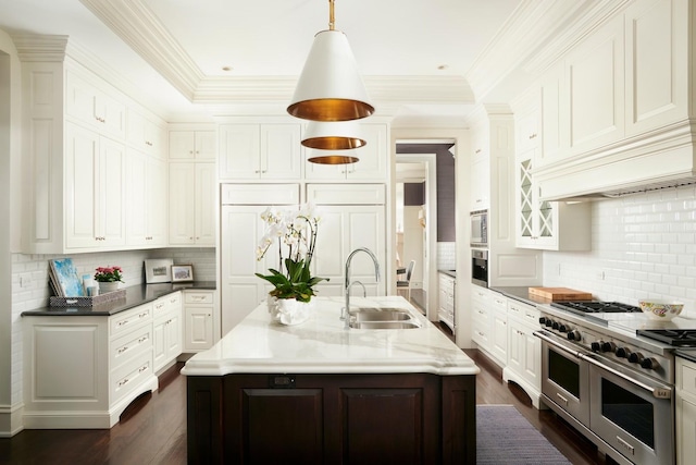 kitchen featuring a sink, a kitchen island with sink, white cabinetry, appliances with stainless steel finishes, and tasteful backsplash