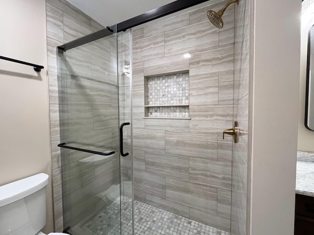 bathroom featuring toilet and a shower with shower door