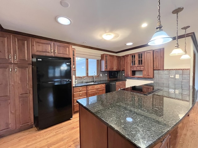 kitchen with sink, dark stone countertops, pendant lighting, black appliances, and light wood-type flooring