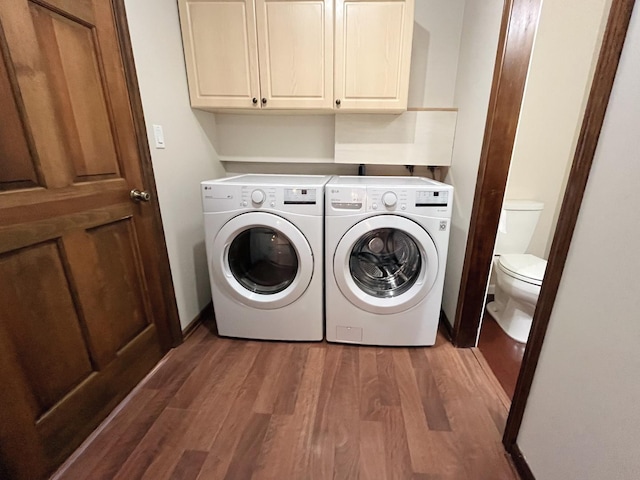 clothes washing area with washing machine and dryer, cabinets, and dark hardwood / wood-style floors