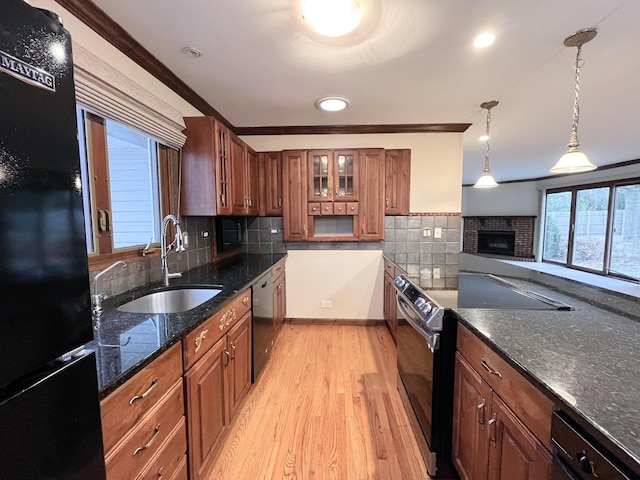 kitchen featuring light wood-type flooring, backsplash, ornamental molding, black appliances, and hanging light fixtures