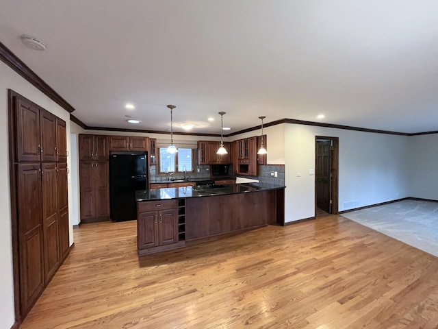 kitchen featuring black fridge, crown molding, hanging light fixtures, and light hardwood / wood-style floors