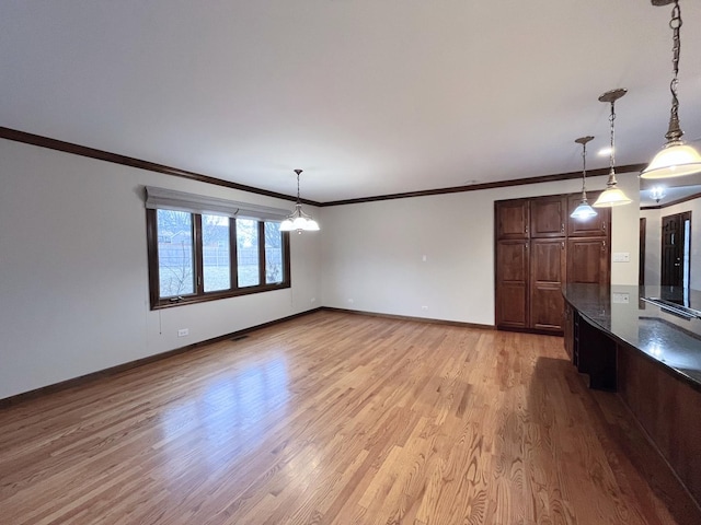 unfurnished living room featuring light hardwood / wood-style flooring, an inviting chandelier, and ornamental molding