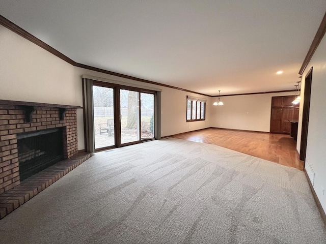 unfurnished living room with light carpet, a fireplace, a notable chandelier, and ornamental molding