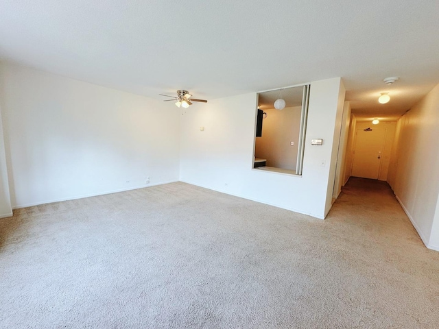 spare room with light colored carpet and a ceiling fan