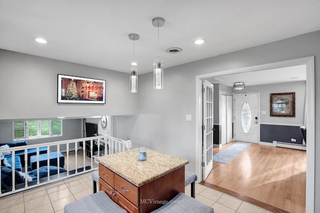 kitchen featuring decorative light fixtures, a kitchen island, light wood-type flooring, and baseboard heating