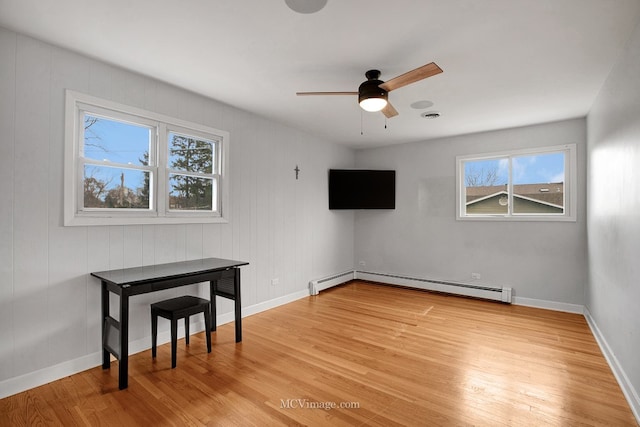 unfurnished room with light hardwood / wood-style flooring, ceiling fan, and a baseboard heating unit