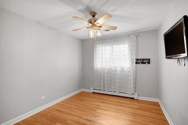 empty room with ceiling fan, light wood-type flooring, and a baseboard heating unit