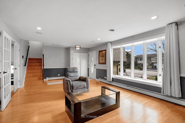 living room with baseboard heating and light hardwood / wood-style floors