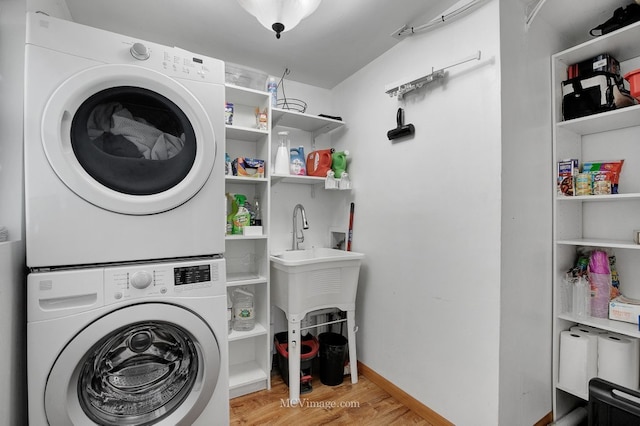 laundry area featuring stacked washer / drying machine and light wood-type flooring