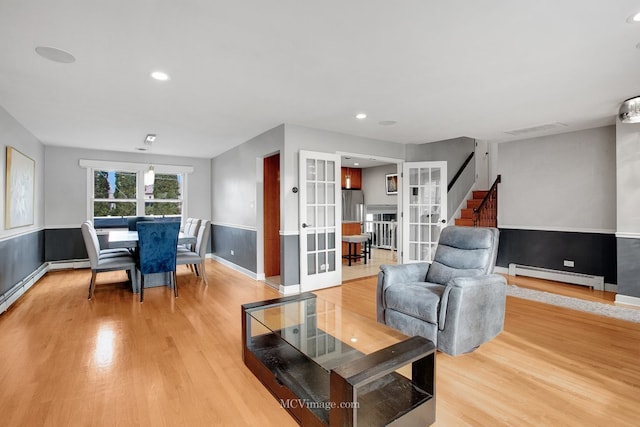 living room featuring french doors, light hardwood / wood-style floors, and a baseboard heating unit