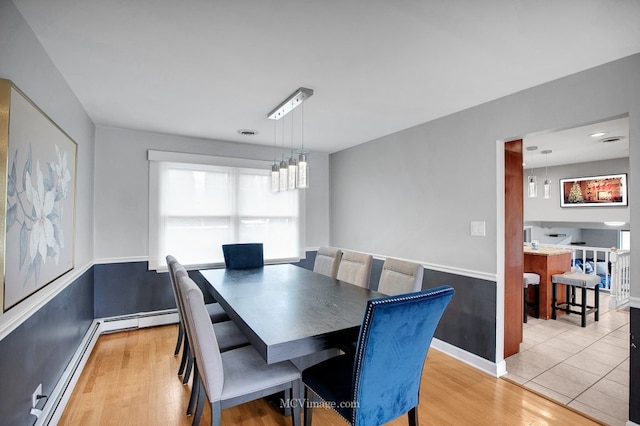 dining room with a notable chandelier, light wood-type flooring, and a baseboard radiator