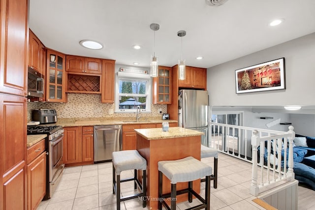 kitchen with a center island, sink, a breakfast bar area, decorative light fixtures, and stainless steel appliances