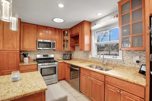 kitchen with sink, light stone counters, pendant lighting, light tile patterned floors, and appliances with stainless steel finishes