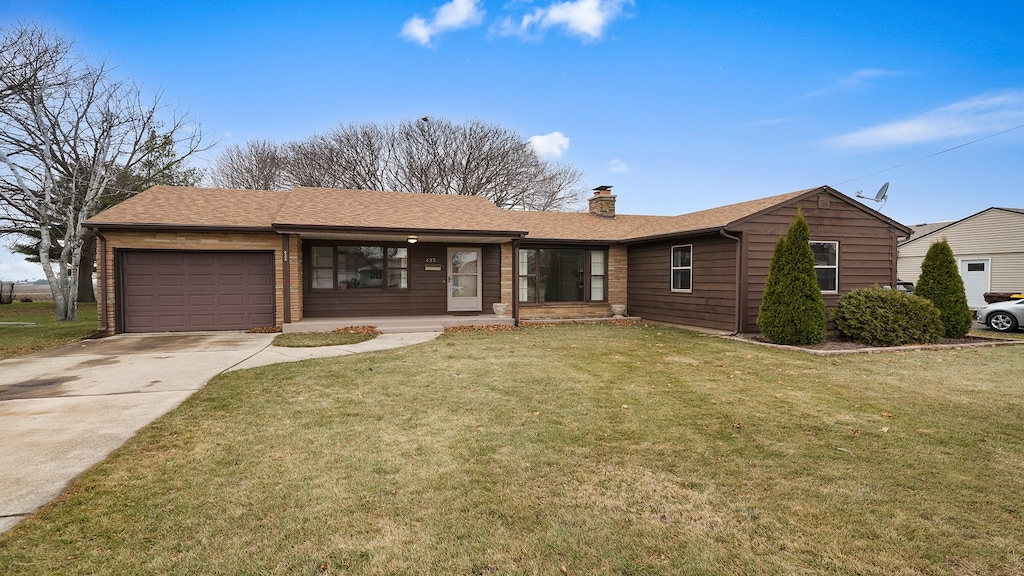 ranch-style house featuring a garage and a front lawn