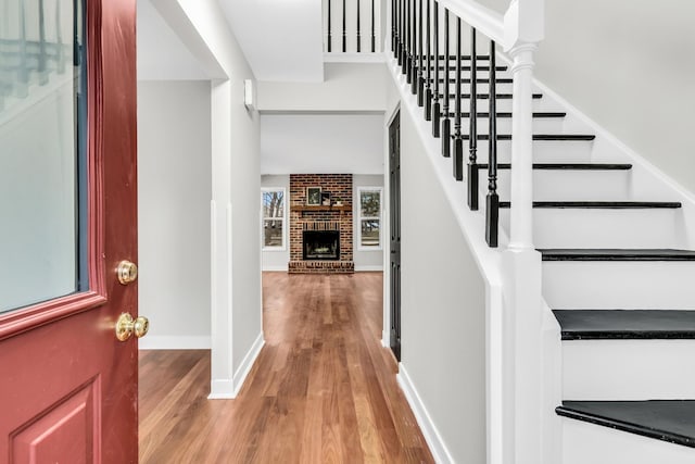 entryway with hardwood / wood-style floors and a brick fireplace