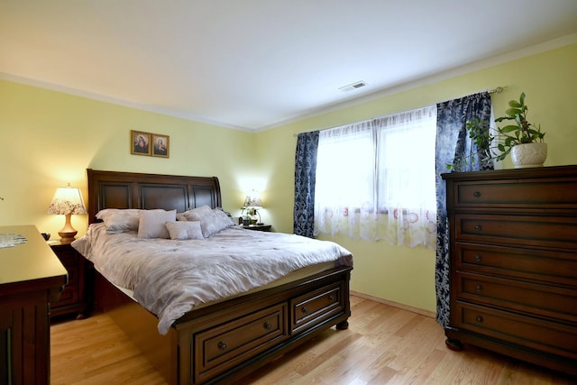 bedroom with light hardwood / wood-style floors and ornamental molding