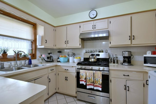 kitchen featuring tasteful backsplash, stainless steel range, sink, light tile patterned floors, and white cabinets