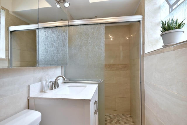 bathroom featuring vanity, toilet, a shower with shower door, and tile walls