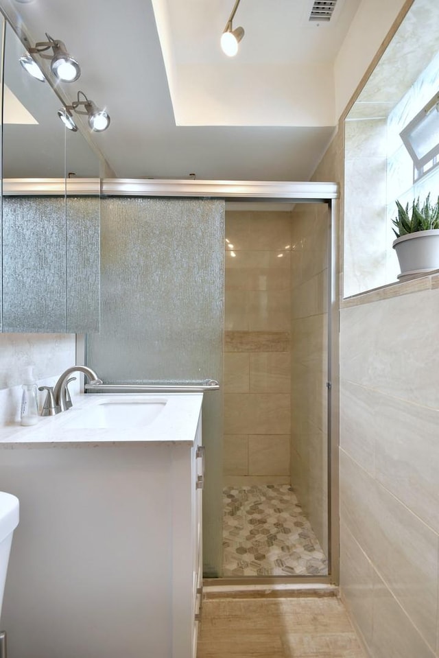 bathroom with hardwood / wood-style flooring, vanity, a shower with shower door, and toilet