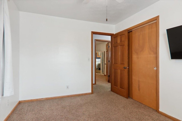 unfurnished bedroom with light carpet, a closet, and ceiling fan